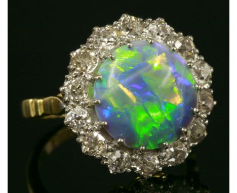 A black opal and diamond circular cluster ring,with a circular cabochon black opal, surrounded by old European cut diamonds, 