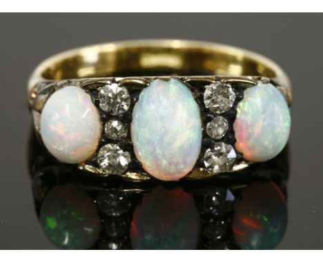 A late Victorian opal and diamond carved head ring,with three graduated oval cabochon opals, with three graduated old Swiss c