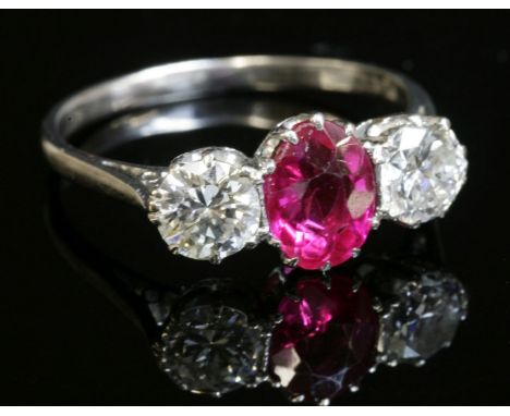 A ruby and diamond three stone ring,with an oval mixed cut ruby, claw set to the centre, with a brilliant cut diamond, claw s