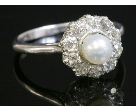 A pearl and diamond circular cluster ring,with a central peg set pearl, surrounded by old European cut diamonds, claw set to 