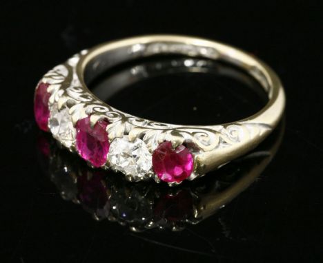 A late Victorian five stone ruby and diamond carved head ring,with later rhodium plated finish.  Three oval mixed cut rubies 