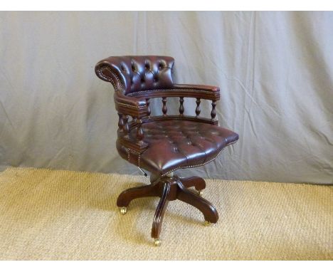 A red leather button back captain's chair on brass castors