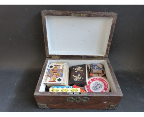 A vintage wooden box with brass decoration containing a collection of playing cards including 19th century examples