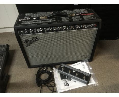 A Fender Deluxe guitar amplifier with footswitch, amp cover and manual.