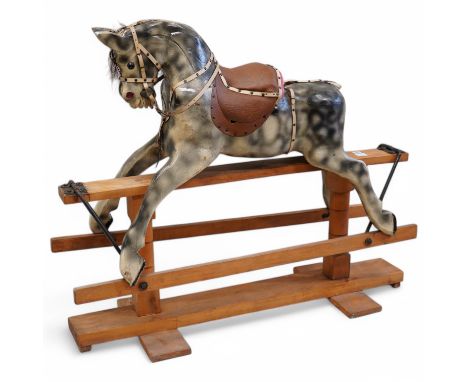 An early 20th century dapple grey rocking horse, on later trestle base, length 132cm. Condition - fair.