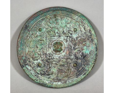 A Chinese Patinated Bronze Circular Mirror of Archaic Form, the plain silvered face with green patination, the verso cast in 