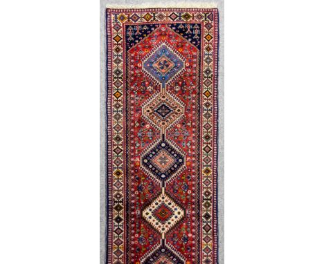 A 20th Century Yalameh Runner, woven in colours of ivory, navy blue and wine, with seven hexagonal stepped medallions, the fi