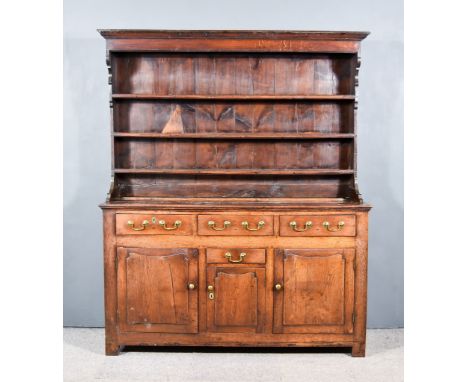 An 18th Century Oak Dresser, the upper part with moulded cornice, fitted three shelves, the base fitted four drawers with cup