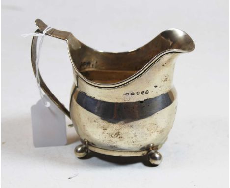 A George III silver cream jug of helmet shape on ball feet, weight 3.9oz