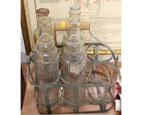 An original galvanised steel six division oil bottle holder containing four examples to include X100 Shell Motor Oil, two Ess