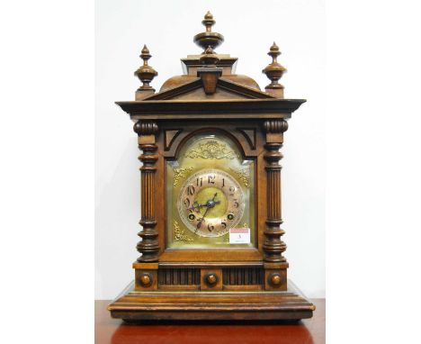 A late 19th century Continental walnut cased mantel clock, of architectural form, having a brass arched dial with silvered ch