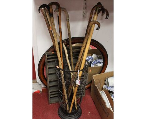 A wirework stick stand containing various walking sticks, together with a printer's tray and oval wall mirror