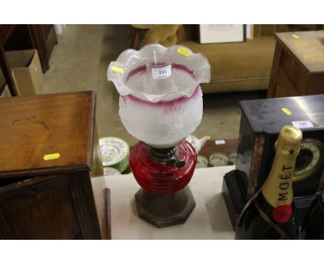 An oil lamp with ruby glass reservoir and frosted shade