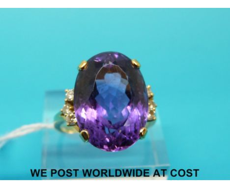 A yellow metal ring marked 18ct set with a large oval cut amethyst with three diamonds to each side (size R/S) 