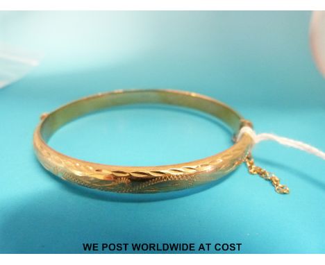 A 9ct gold bangle with chased decoration (8.6g)