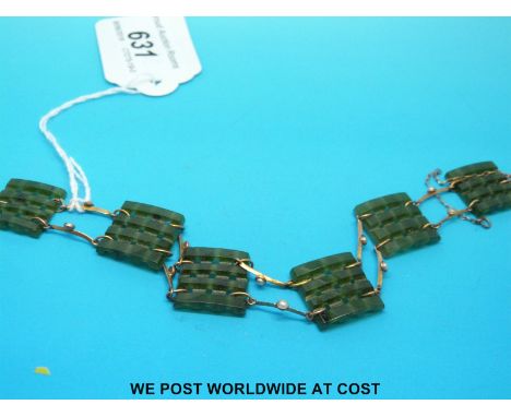 A yellow metal bracelet set with square pierced sections of spinach jade separated by bars of yellow metal set with a seed pe