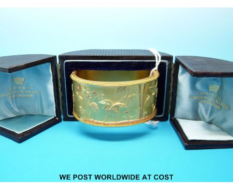 A Victorian yellow metal bangle with Japanese style design depicting storks and bamboo, in original Martin & Co fitted box 