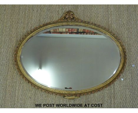 A 19thC oval mirror with gilt plaster work and wooden frame ornately decorated with ribbon twist border and rococo finial, th