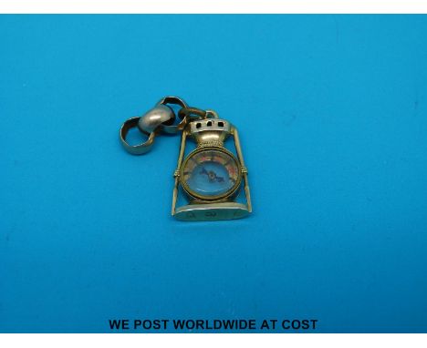 A hallmarked 10ct gold charm in the form of a lamp with a compass to the centre 