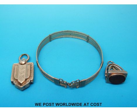A yellow metal bangle, Victorian locket with chased decoration and a hallmarked 9ct gold fob. 