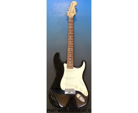 A Squire Strat electric guitar by Fender, in black finish together with a Marshall Valvestate 10 practice amplifier