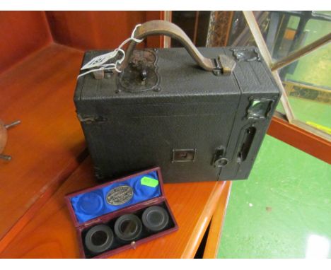 An Ensign falling plate bellows camera and a case of three lenses from the Stereoscopic Photographic Co