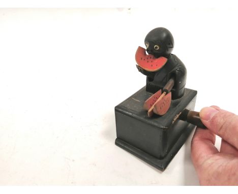 A novelty early 20th Century treen toy automaton of a bald headed figure chopping and munching on watermelon,  tilting his he
