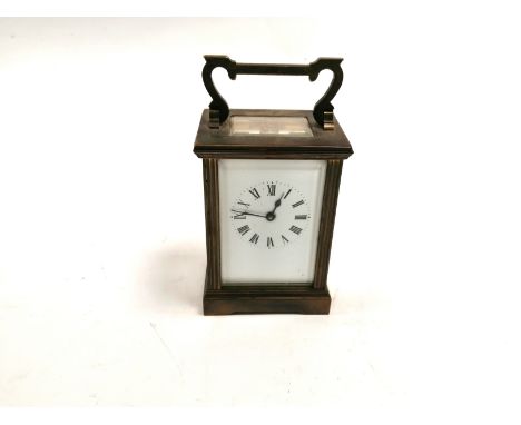 A brass carriage clock with enamel dial and Roman numerals,  with inspection labels to the base for the antique clock clinic 