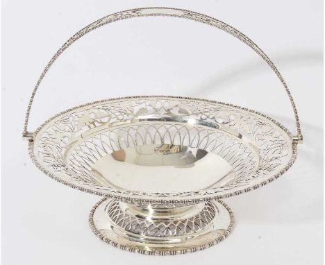 George V silver cake basket of circular form with pierced foliate decoration, egg and dart borders and swing handle, raised o