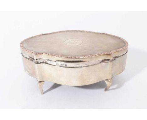 George V silver jewellery box of oval form with engine turned decoration and decorative scroll borders, hinged cover, opening