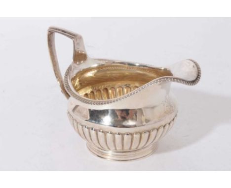 George III silver cream jug of half-fluted potbellied form, with engraved crest, 5.8ozs