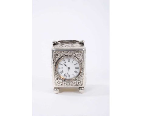 Victorian silver cased carriage clock with circular white enamelled dial, floral repousse decorated case with swing handle ra