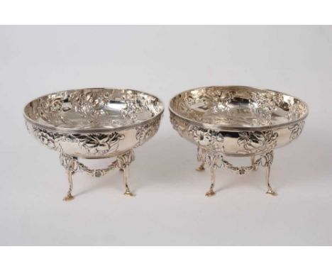 Pair of Edwardian silver dishes of circular form with embossed wrythen floral decoration below reeded borders, raised on sepa