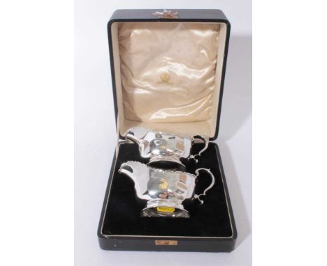Pair of George V silver sauce boats of helmet form with faceted decoration and scroll handles, raised on oval pedestal feet, 