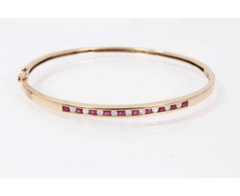9ct gold ruby and diamond hinged bangle with a line of channel set rubies alternating with brilliant cut diamonds. Condition 
