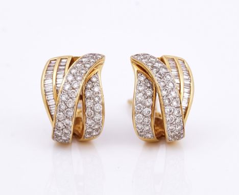 A pair of gold and diamond earclipsEach in a curved and shallow scrolling design, mounted with circular cut and baguette diam