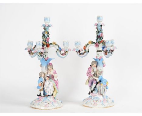 A pair of German porcelain four-light candelabraEarly 20th century, modelled as a seated fashionable couple with children aro