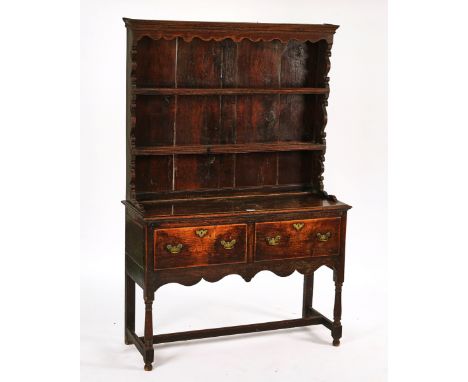 AN 18TH CENTURY SMALL OAK DRESSERWith enclosed plate rack over a pair of drawers, on turned supports, 125cm wide; 188cm high 