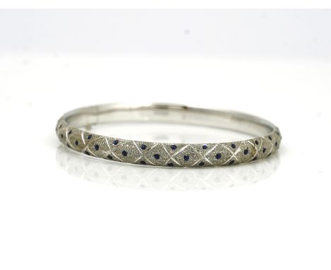 A blue enamelled and white gold hinged bangleof rounded design, with blue enamelled beaded decoration and otherwise with a te