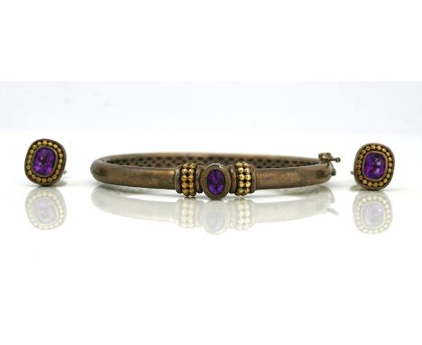 An amethyst set silver and gold hinged bangle and a pair of earrings, (2)The bangle mounted with an oval cut amethyst, betwee