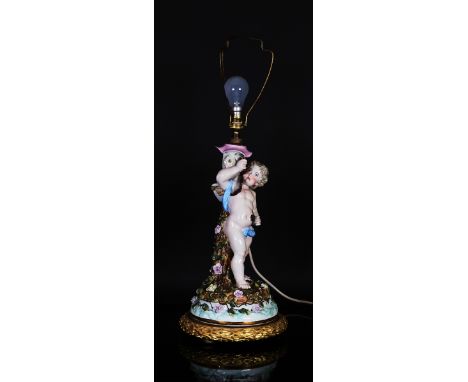 A Sitzendorf porcelain lamp baseLate 19th/early 20th centuryOriginally a candelabrum or centrepiece, modelled as Cupid holdin