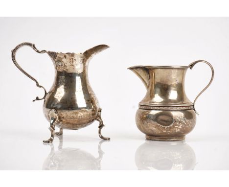 A silver cream jug and another (2)The first of baluster form, with a scrolled handle, raised on three feet in the 18th centur