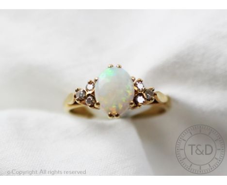 An opal and diamond ring, the central oval opal flanked by three diamonds to either side, all claw set in yellow metal to the