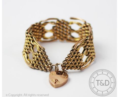 A yellow metal 'gate' type bracelet, with tapering terminals and attached heart shaped padlock clasp stamped '9ct', gross wei