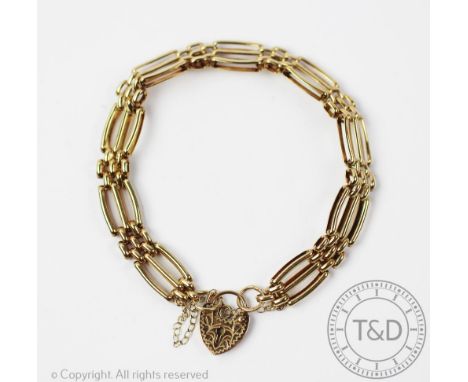 A 9ct yellow gold 'gate' type bracelet, designed as slender three bar gate links, tapering to a heart shaped padlock clasp an