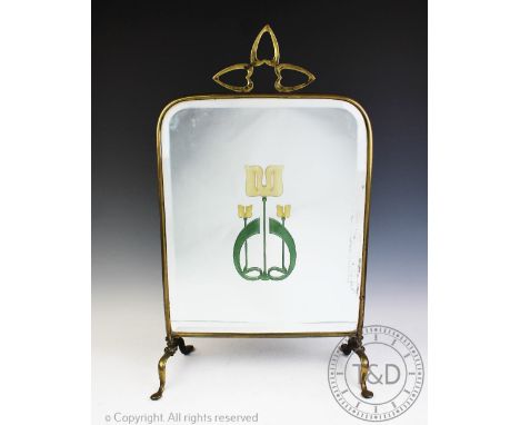 An Art Nouveau brass fire screen set with bevelled glass, with trefoil shaped handle and central Art Nouveau motif, 63cm high