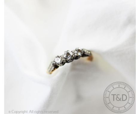 A three stone diamond ring, designed as three graduated brilliant cut diamonds, all set in white metal to the faceted shoulde