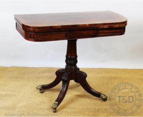 A Regency mahogany and rosewood card table, with turned and carved column, on carved and reeded legs, 75cm H x 91cm W x 46cm 