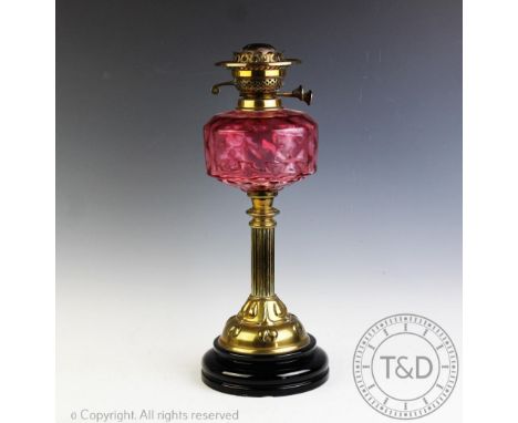 A Victorian brass oil lamp, with moulded cranberry glass reservoir, on a fluted column and moulded base, 46cm CONDITION REPOR