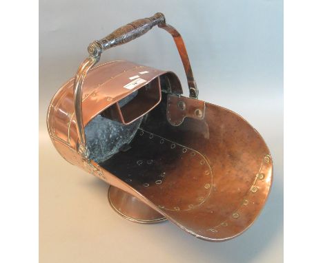Copper helmet shaped coal scuttle with turned wooden swing handle. (B.P. 21% + VAT) Handle is loose, dinks and dents.Please n